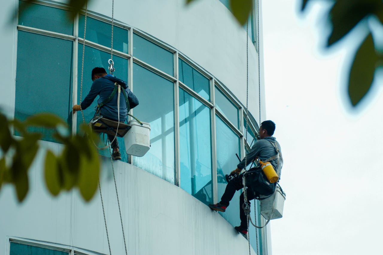 Window cleaners suspended on ropes clean a high-rise buildings glass exterior.